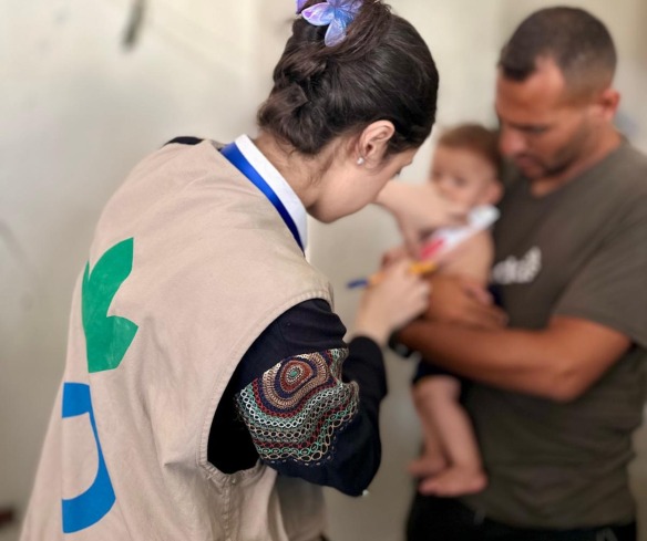 Health worker screens a child for severe malnutrition in Gaza.