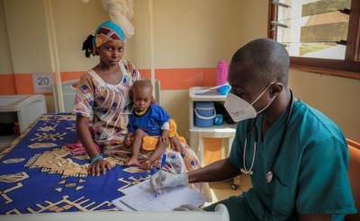 A healthcare worker in a mask with a mother and child at the pediatric hospital in Bangui, Central African Republic.
