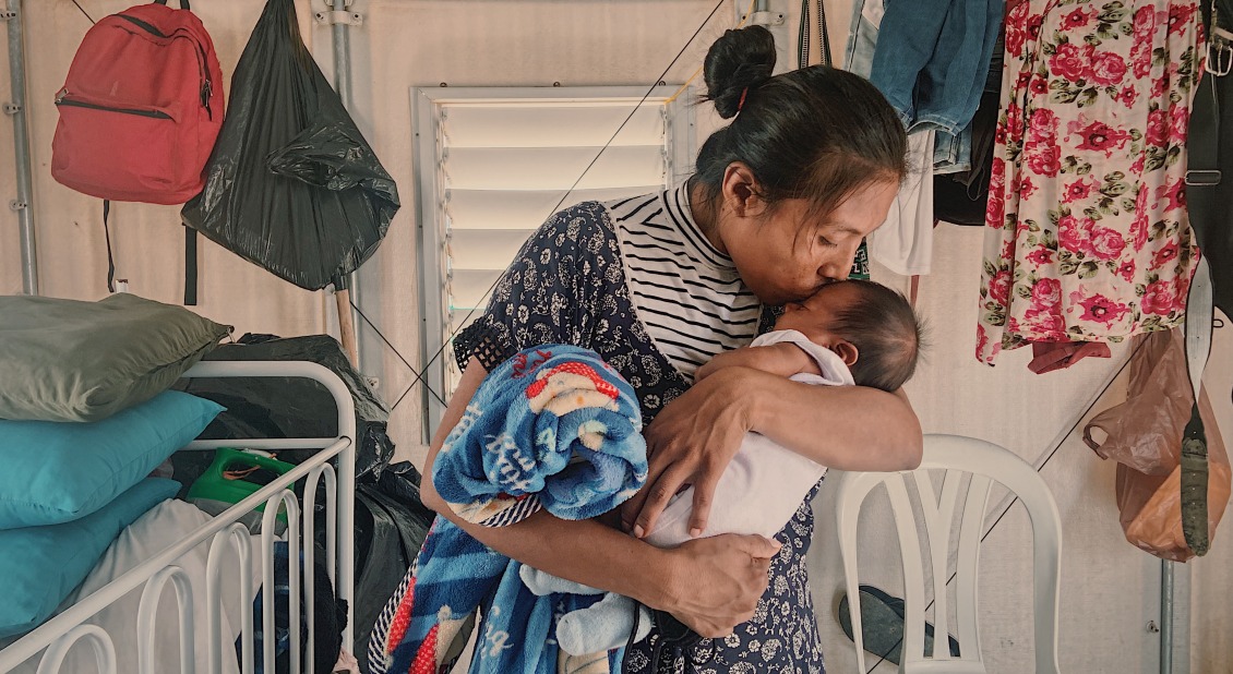 A mother kisses her baby. Her family was displaced by conflict and now receives cash support from Action Against Hunger.
