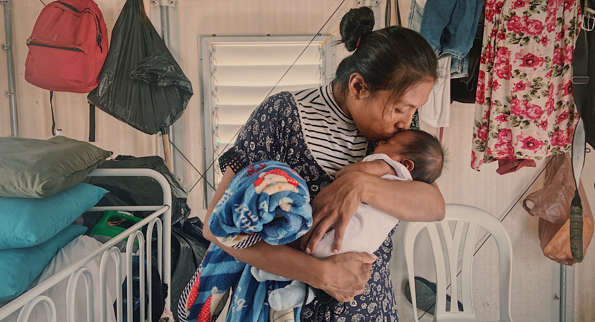 A mother kisses her baby. Her family was displaced by conflict and now receives cash support from Action Against Hunger.