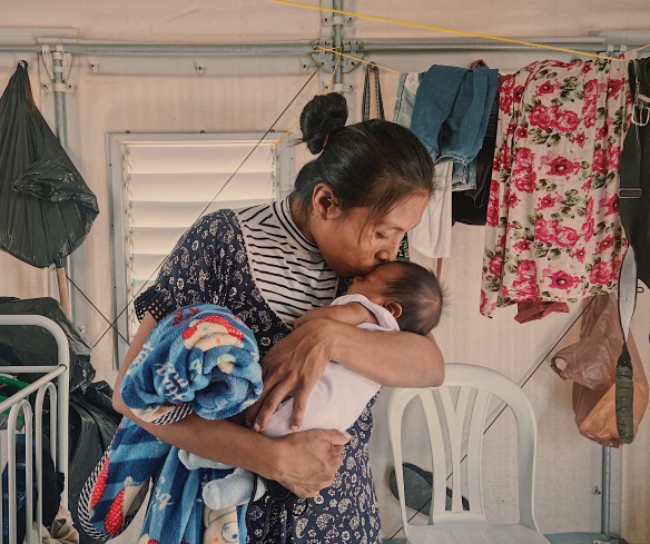 A mother kisses her baby. Her family was displaced by conflict and now receives cash support from Action Against Hunger.