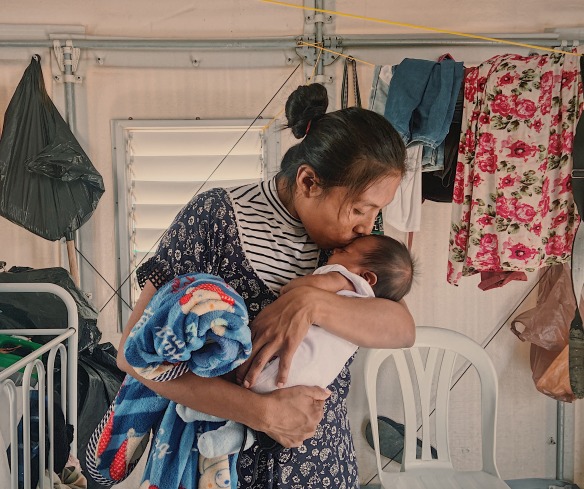 A mother kisses her baby. Her family was displaced by conflict and now receives cash support from Action Against Hunger.