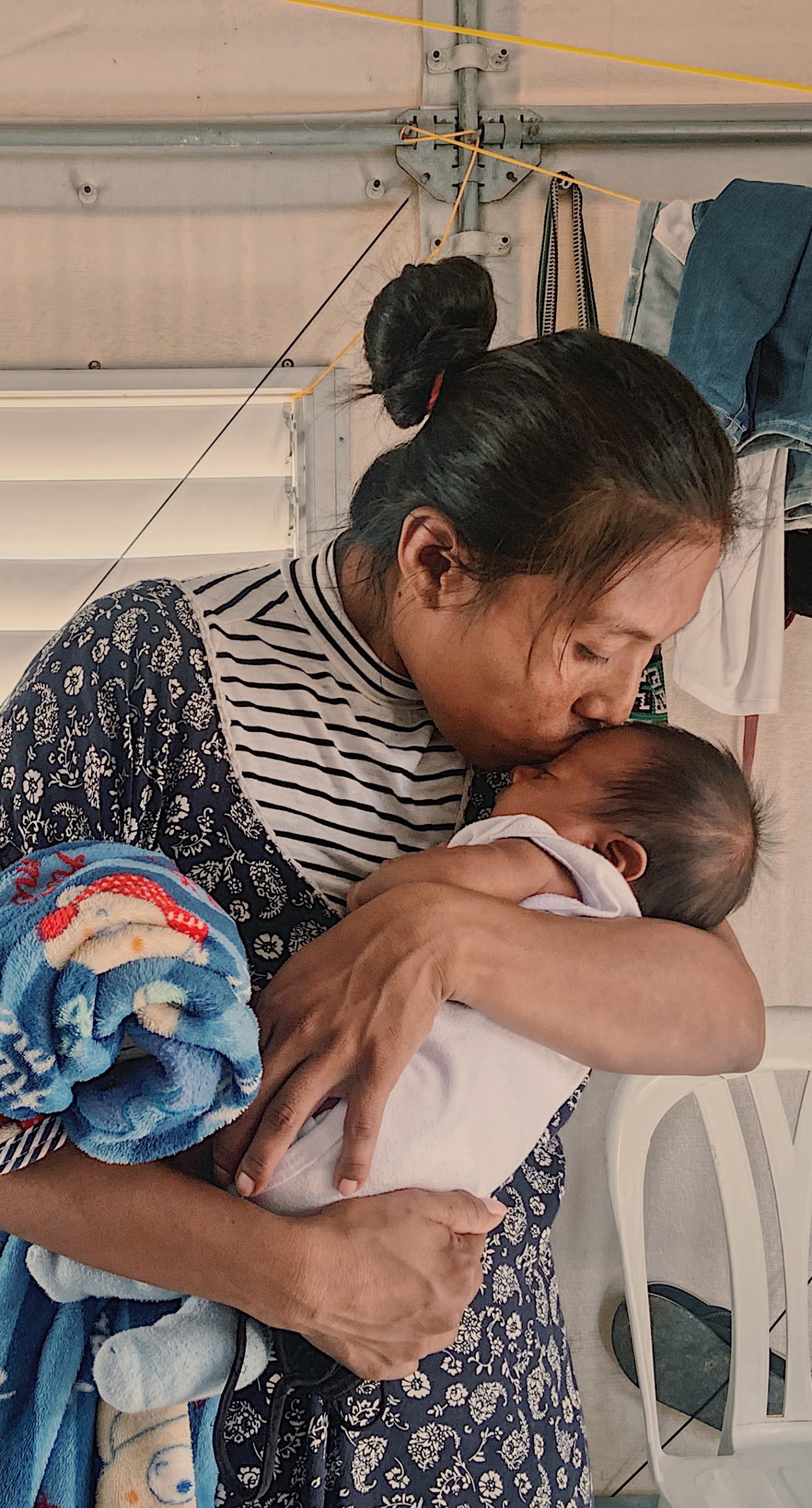 A mother kisses her baby. Her family was displaced by conflict and now receives cash support from Action Against Hunger.