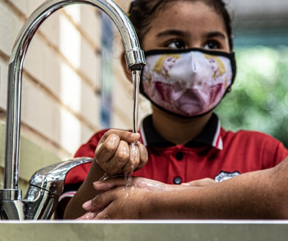 A girl washes her hands.
