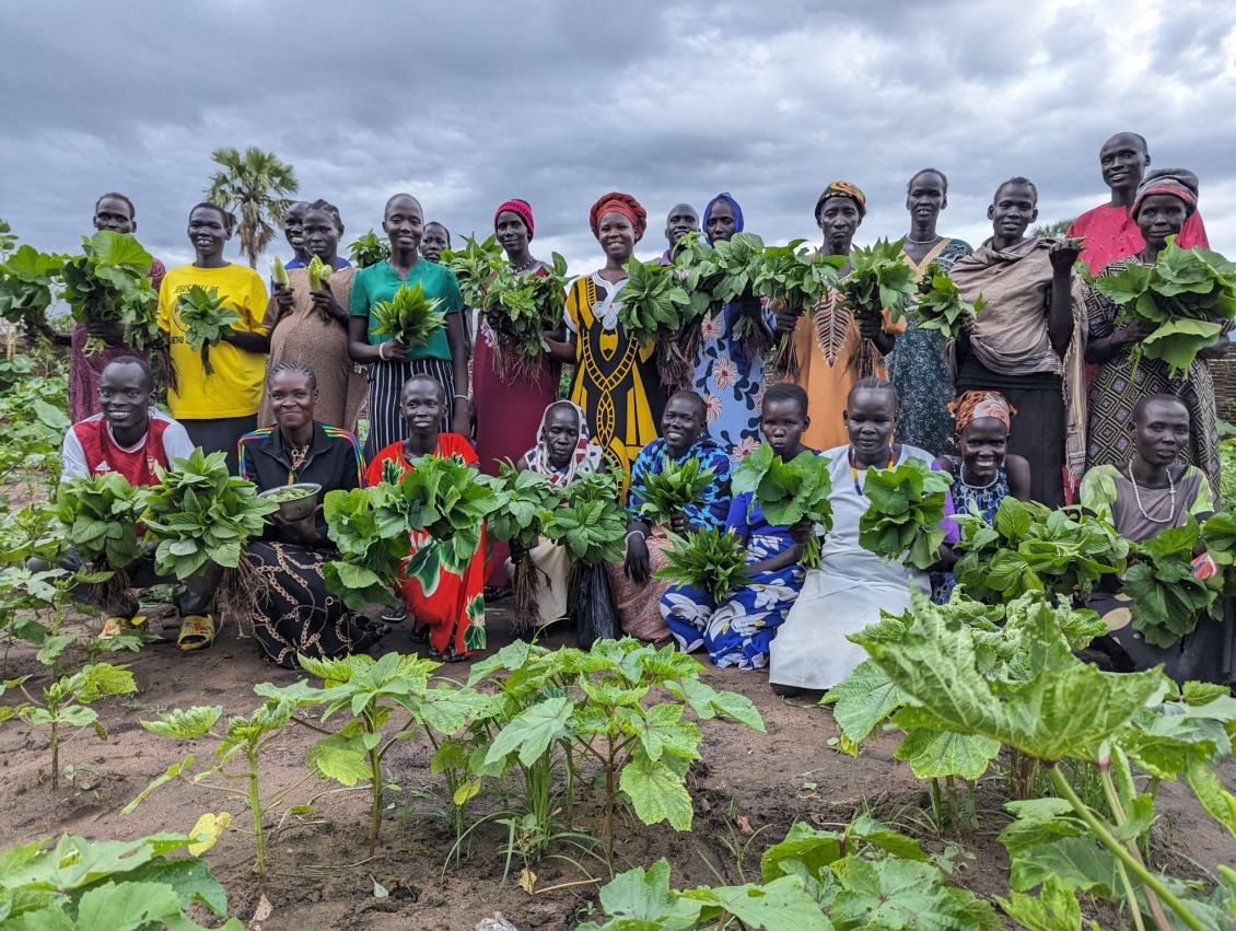 A group of women pose with the vegetables they grew.