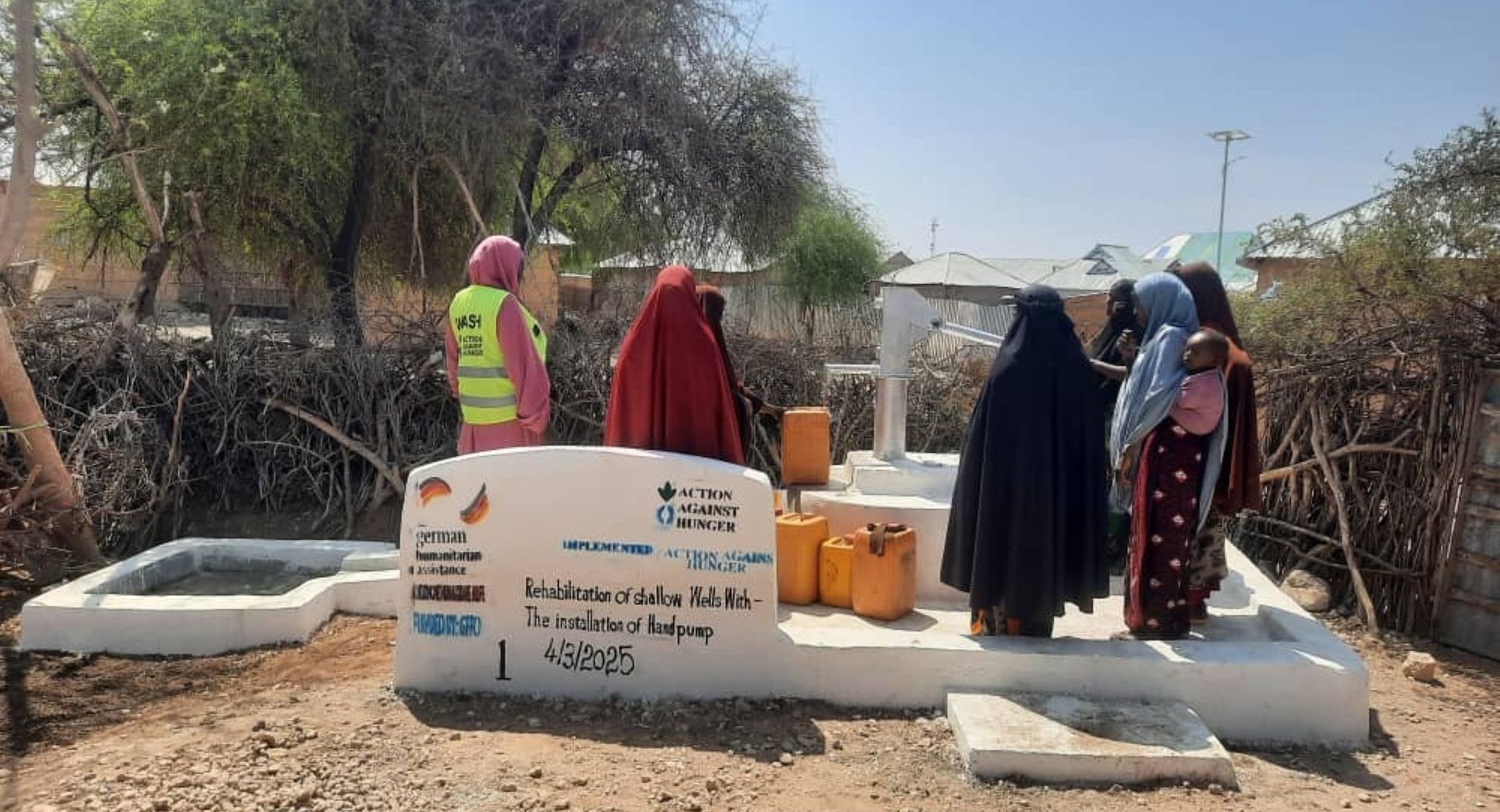 Community members drawing water from the rehabilitated well