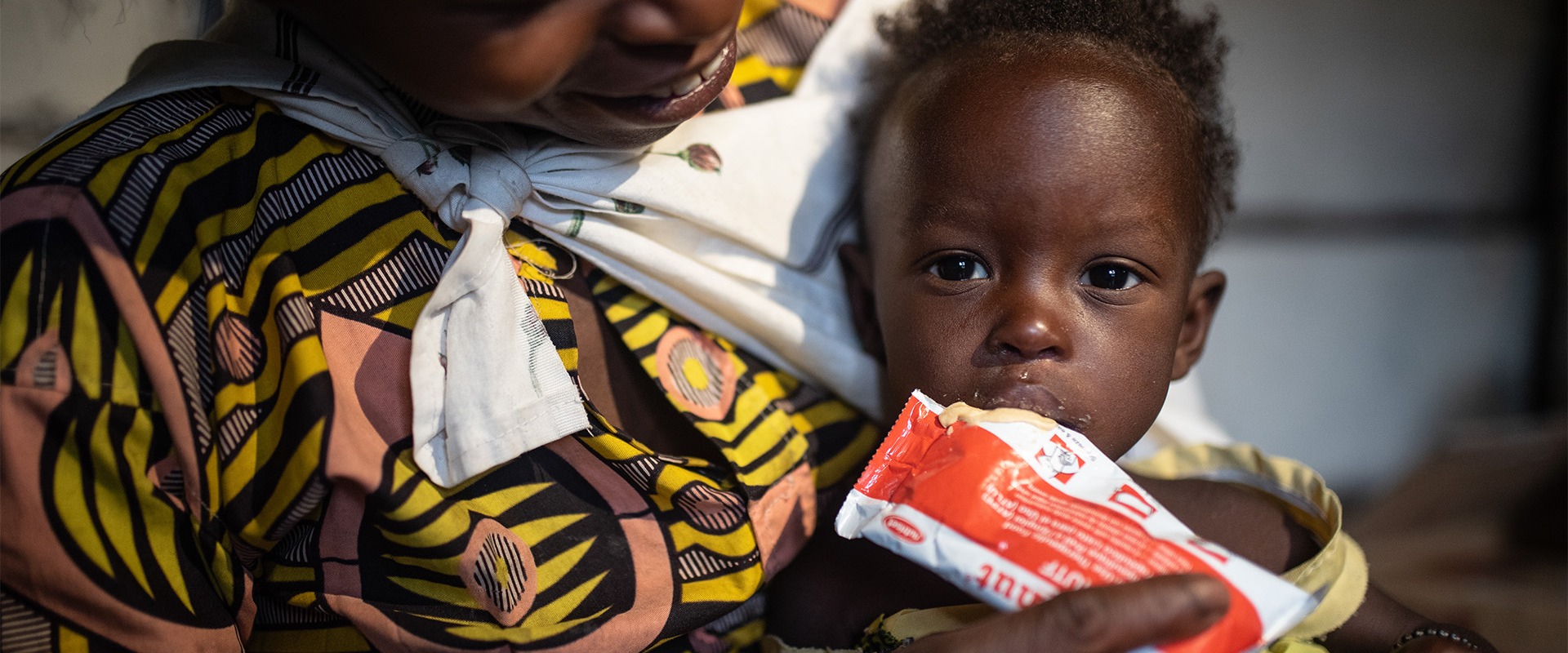 A mother feeds Plumpy'nut to her child.
