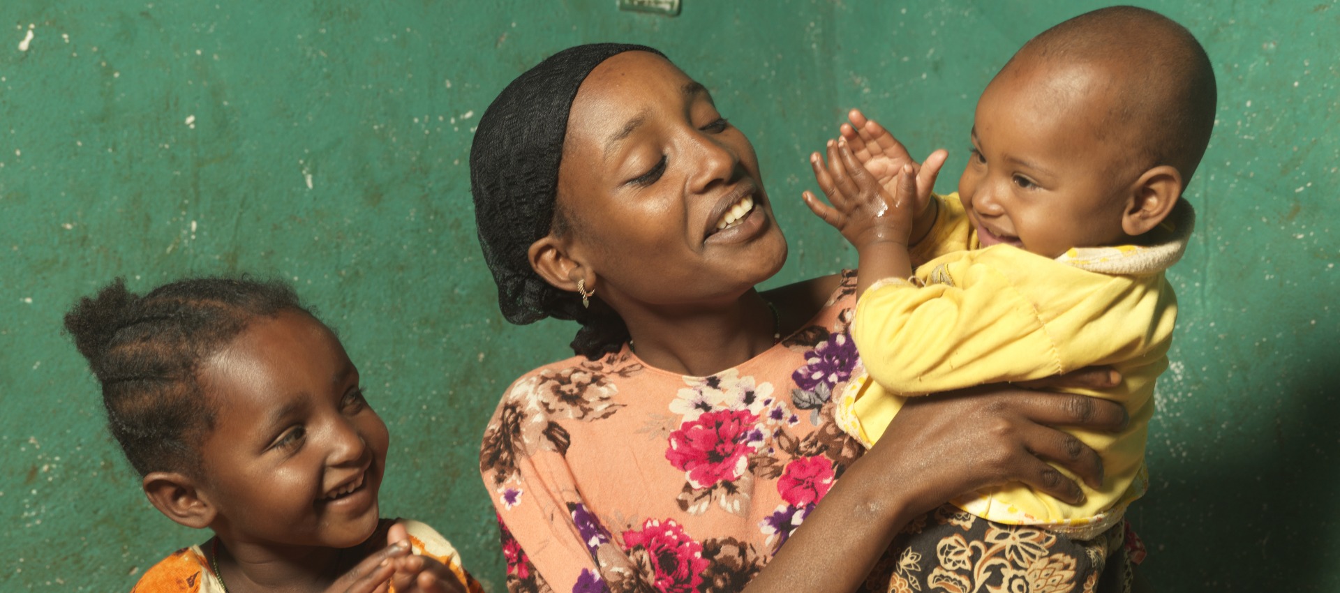 A mother laughs with her two children.