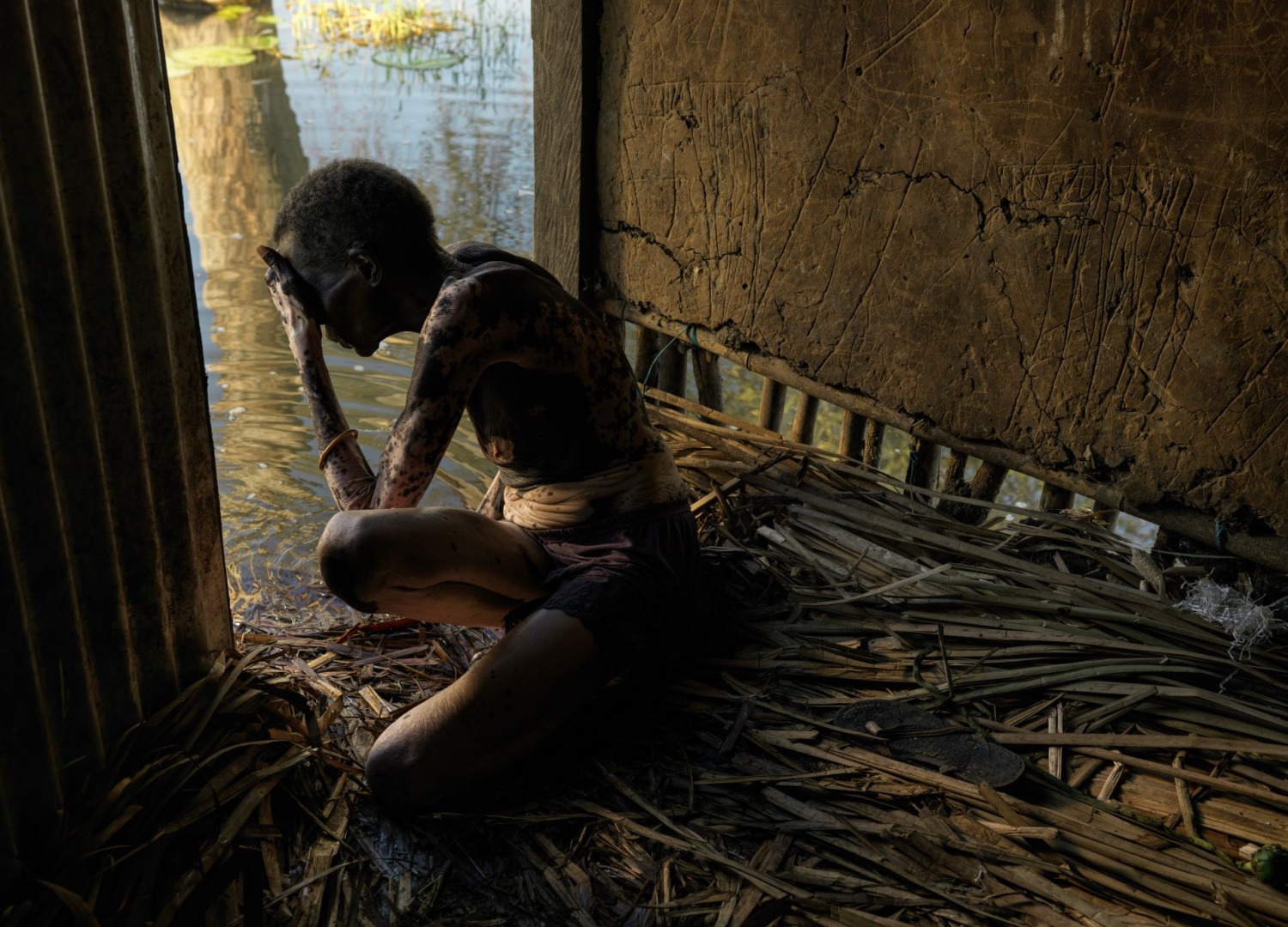A woman sitting in a flood at home in South Sudan.