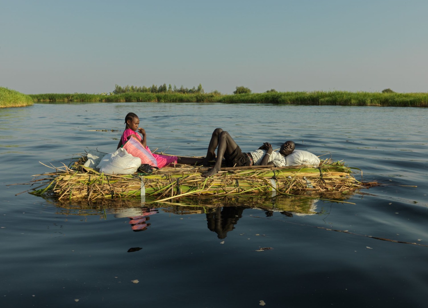 A man and child on a straw raft in flooded waters in South Sudan