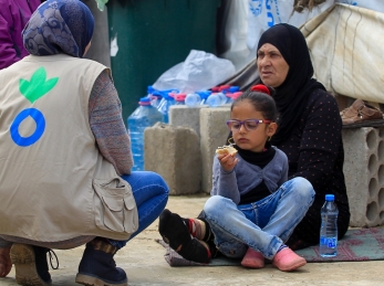 An Action Against Hunger aid worker talks with a refugee family in Lebanon.