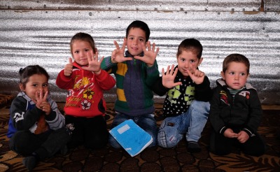 Ali, middle, and his siblings use their fingers to share their ages. Their family is from Raqqa, Syria, and fled to Lebanon as refugees.
