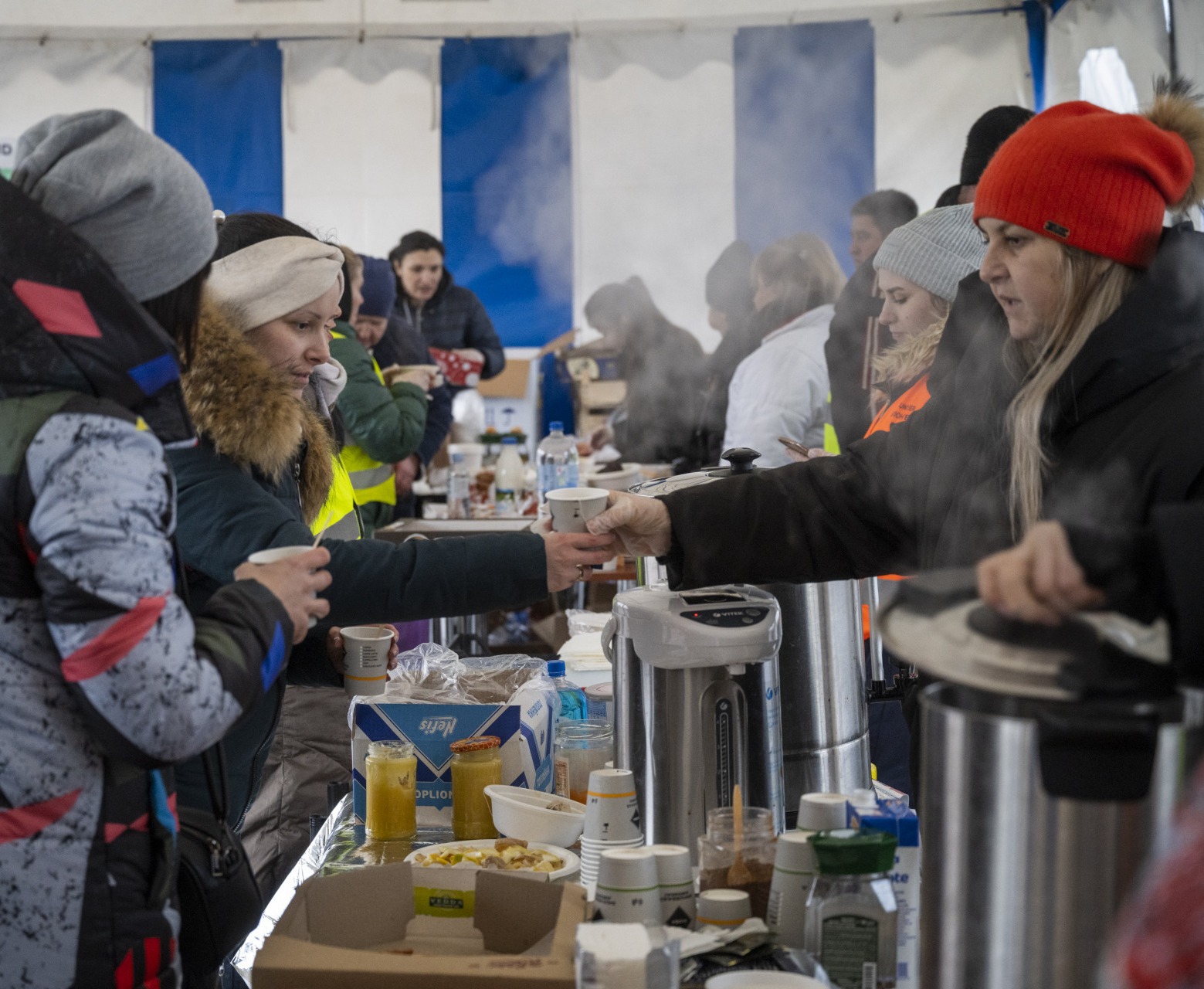 Staff and volunteers distribute hot meals and drinks to Ukrainian refugees.