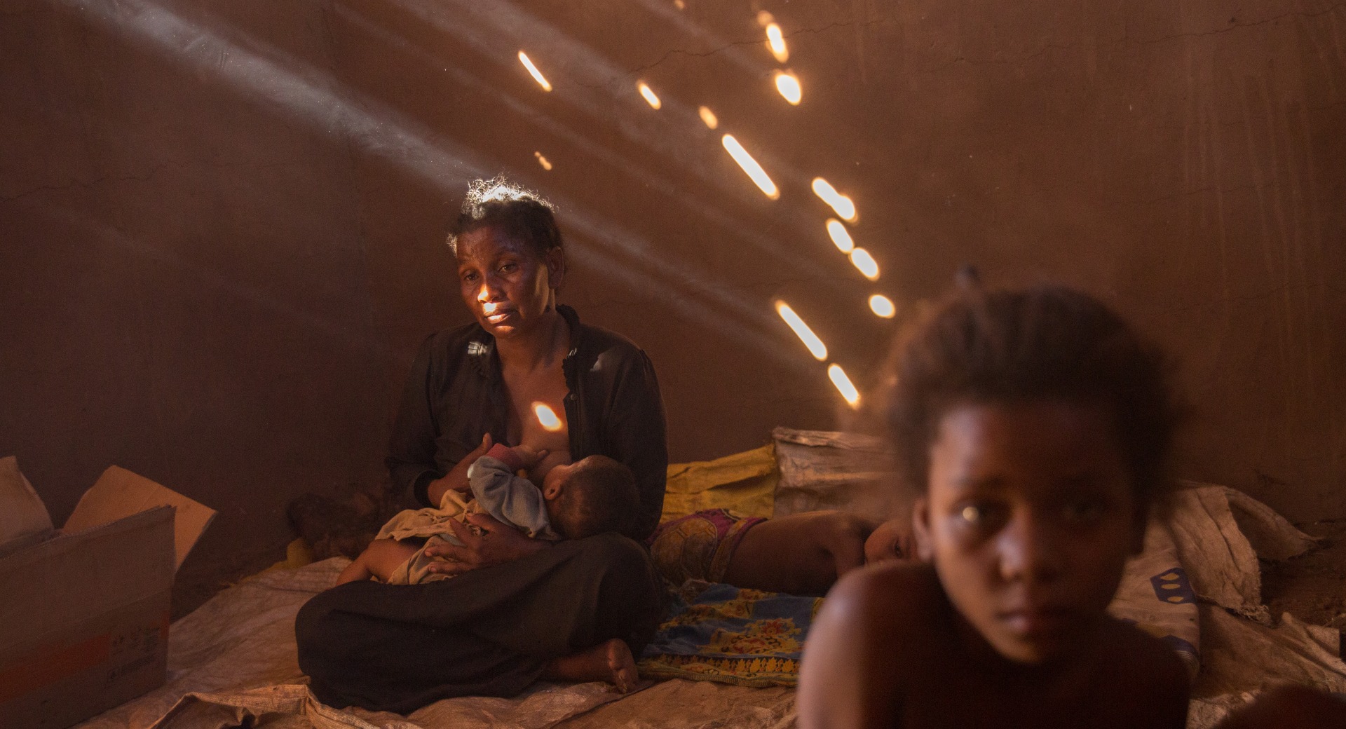 A mother breastfeeds her child in her home.