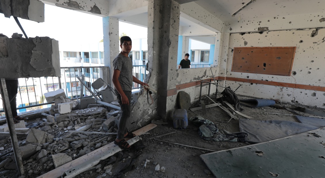 Two children walk in a destroyed classroom in Gaza/ © WeWorld in partnership with Action Against Hunger.