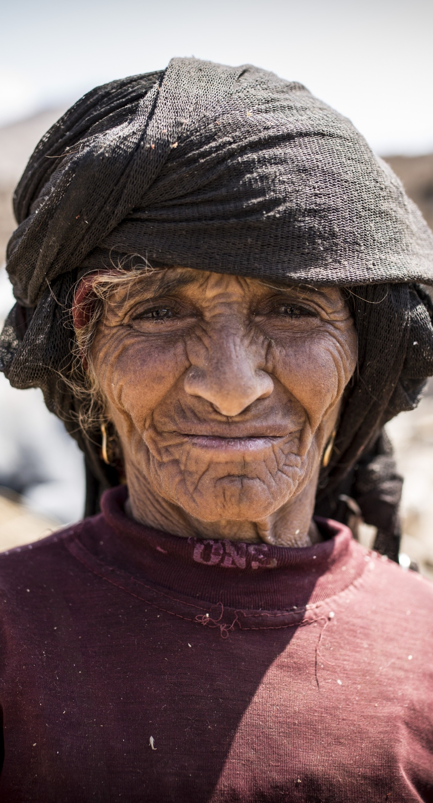 In Yemen, a woman stands in front of her community, which has been destroyed by conflict.