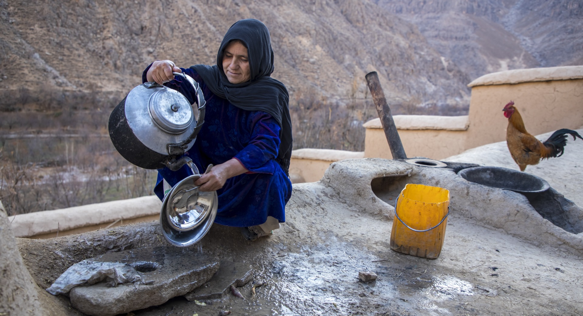 Mahnaz washes her dishes outside her home compound in Duykondi Province, Afghanistan. Action Against Hunger works in this area to manage feeding programs and provide mobile health and nutrition support.