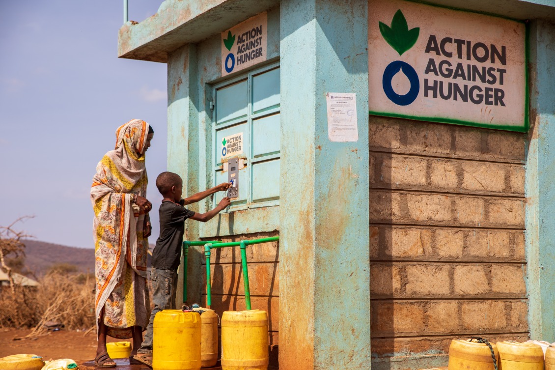 A woman and child bottling water at an Action Against Hunger Smart Tap