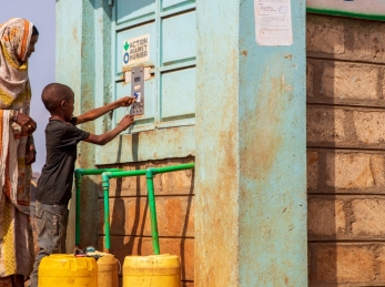 A woman and child bottling water at an Action Against Hunger Smart Tap