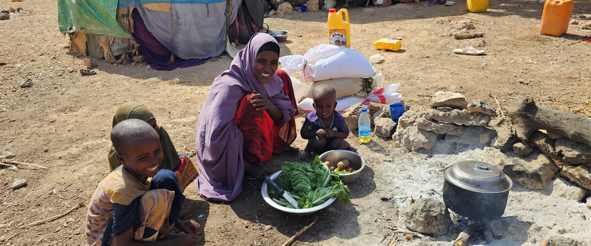 A woman and three children cooking in a displaced community in Somalia.