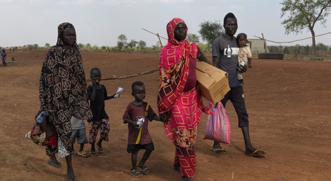 A group of six refugees walk with belongings near the South Sudan border