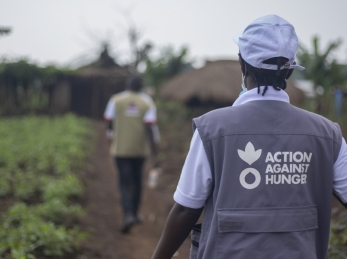 An Action Against Hunger aid worker walks through a field.