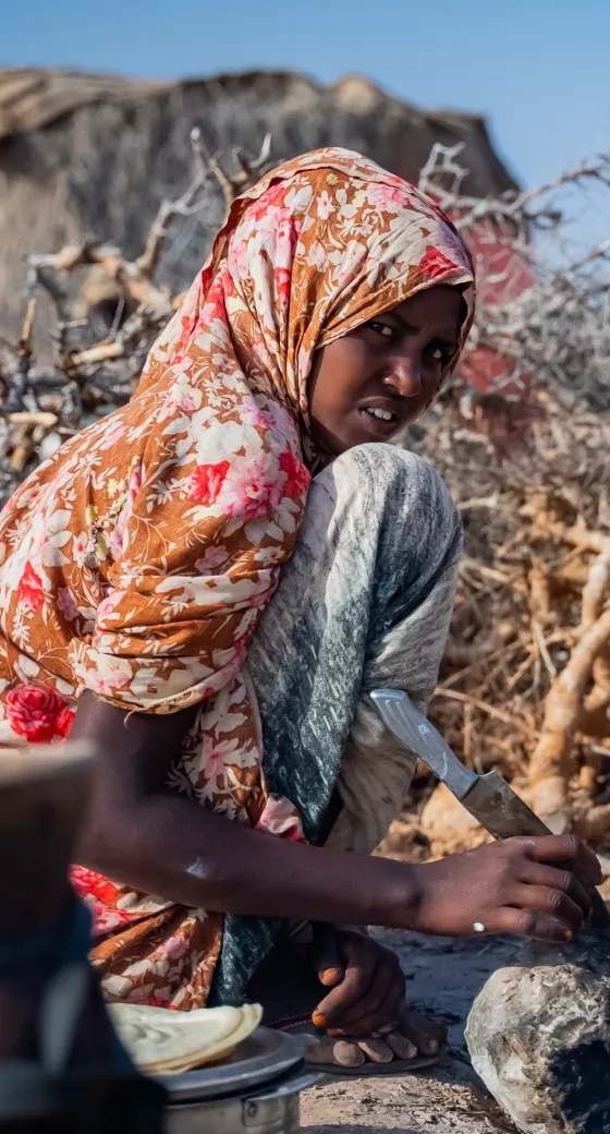 A girl, 16, makes breakfast for her family in a drought in Somalia.