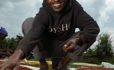 A man harvesting legumes and smiling in Uganda.