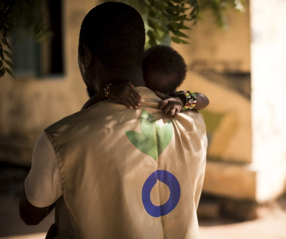 An Action Against Hunger Aid Worker holds a child in his arms in Mali.